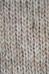 The texture of fabric thick beige sweater close-up. Knitted texture background
