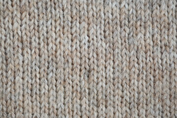 The texture of fabric thick beige sweater close-up. Knitted texture background