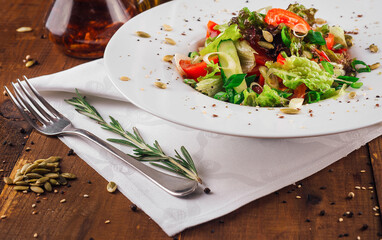 Fresh vegetable salad with spices and oil dressing on wooden table