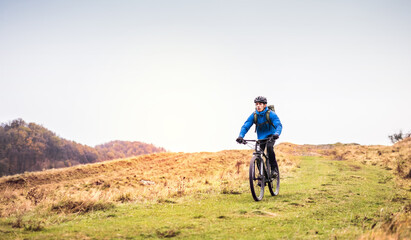 Fototapeta premium Active man on bike in the middle of beautiful nature, early autumn morning. Concept of healthy lifestyle.