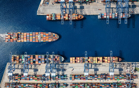 Aerial top down view of a large container cargo ship terminal harbor with loading activity and vessel traffic