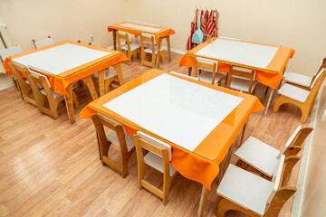 Classroom with small tables and chairs covered with orange tablecloths