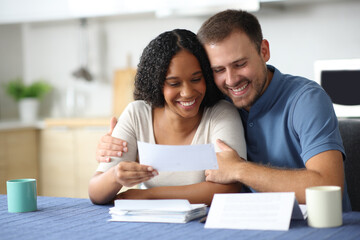 Happy interracial couple checking receipt at home