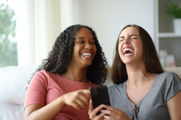 Interracial couple laughing checking smart phone at home