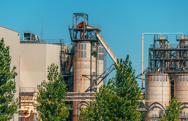 Obraz premium Wood processing plant exterior, timber industry building with tree trunks stacked