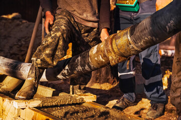 Adding pipes for a concrete pump.Concrete mix truck service pouring cement in construction site during daytime. 