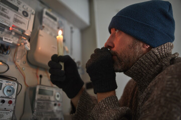 Checking the electricity power meter with a candle in cold winter days while there is power outage.
