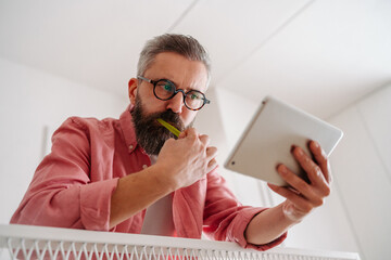 Man using smart thermostat while brushing teeth in bathroom. Concept of sustainable, efficient, and smart technology in home heating and thermostats.