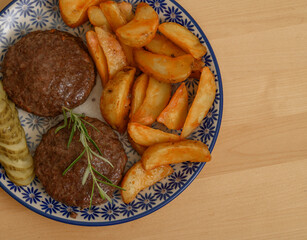 Obiad na talerzu z bliska, kotlety mielone z frytkami z ziemniaków i ogorkiem