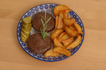 Obiad na talerzu ziemniaki mięso i ogórek, kotlety burgery z wołowiny