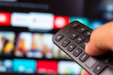 Tv online. Television streaming video. Media TV on demand. Online Multimedia video concept on TV set in dark room. Watching online TV with remote control in hand.