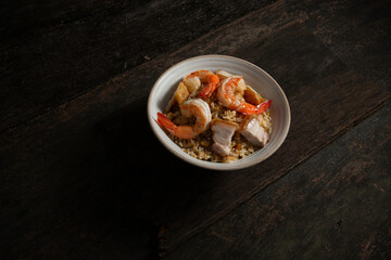 fried rice with with crispy pork and shrimp in light brown bowl on old wooden table
