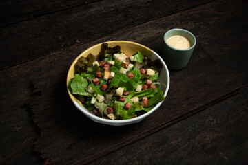 Caesar salad with salad dressing on old wooden table