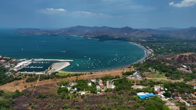 Drone approaching the Potrero beach and Marina Flamingo, sunny day in Costa Rica