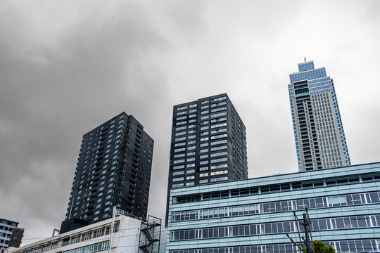 A cluster of modern skyscrapers rises against a dark, overcast sky, showcasing the architectural elegance and urban landscape of the bustling cityscape  in Rotterdam