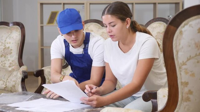 Young woman signs a contract for the provision of services to a plumber guy who came to fix the faucet in the kitchen. High quality 4k footage