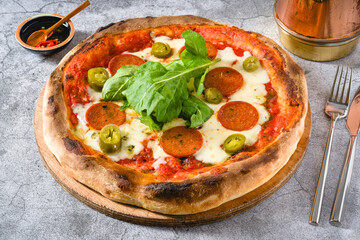 Top view of Neapolitan pizza with sausage, jalapeno peppers and arugula