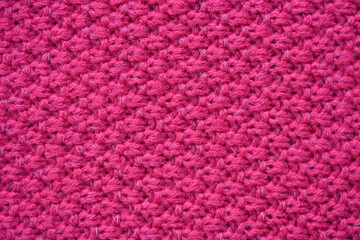 pink texture of knitted wool fabric as a background, smooth symmetrical lines of hand-knitted needlework pattern
