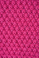 pink texture of knitted wool fabric as a background, smooth symmetrical lines of hand-knitted needlework pattern