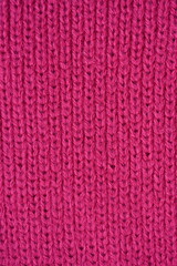 pink texture of knitted wool fabric as a background, smooth symmetrical lines of hand-knitted needlework pattern