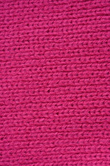 pink texture of knitted wool fabric as a background, smooth symmetrical lines of hand-knitted needlework pattern