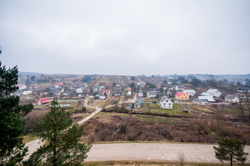 Serene Landscape of a Tranquil Village Amidst Rolling Hills and Gloomy Skies