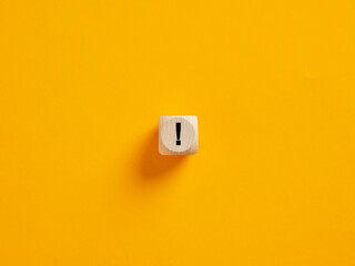 Wooden cube showing an exclamation mark on yellow background