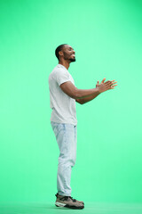 A man, full-length, on a green background, claps