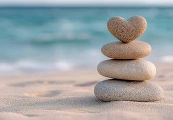 Stacked stones with heart-shaped rock on beach