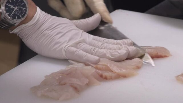 주방 도마 위에서 칼로 생선회를 뜨는 모습