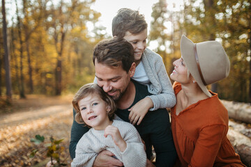 Portrait of family sitting in the middle autumn forest. Nuclear family spending weekend outdoors.
