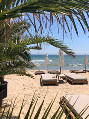 Sandy beach with soft sunbeds and umbrellas.