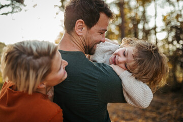 Parents and girl during walk in autumn forest. Girl having fun outdoors.