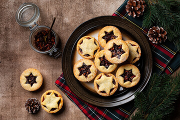 Brown food table with traditional Christmas Mince pies on a plate sprinkled with sugar. Also called...