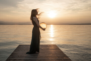 woman in motion hugging a surreal sphere illuminated by the sun that releases energy, abstract concept