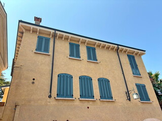 A view of a house with closed ancient shutters that can often be found in small towns in Italy.