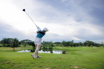  asian women professional swings golf club on golf course