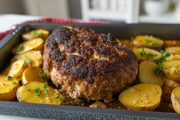 Fresh cooked whole meatloaf with potatoes on a baking tray. Delicious homemade food