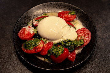 Black Plate with tomatoes, burrata cheese and pesto sauce