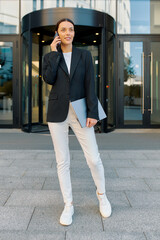 European woman in black jacket uses phone to arrange meeting time with business partner