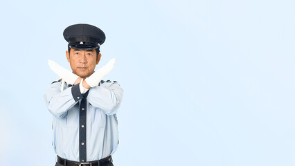 手でバツ印を見せる男性警備員