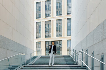Fototapeta premium Young European woman with laptop in hands stands at the entrance to the company's central office
