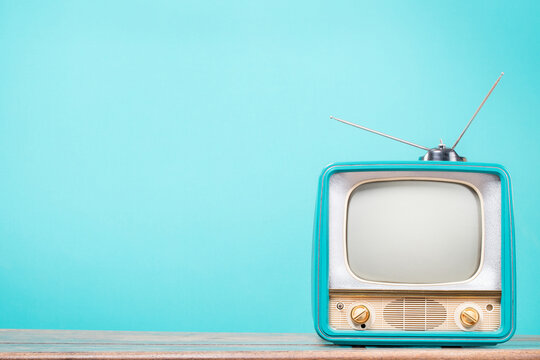 Retro CRT TV with antenna on old table front gradient mint blue background. Vintage style filtered photo