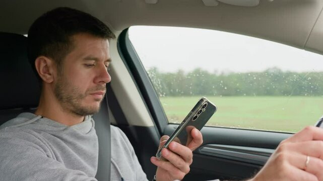 Driver using smartphone while driving car, distracted by messages on his phone. Dangerous driving of a vehicle, violation of traffic rules