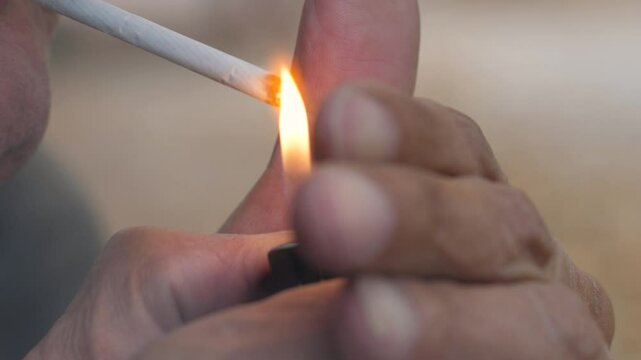 man lighting a cigarette with a lighter, hands of a man holding a lighter and a cigarette