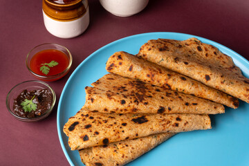 Healthy Indian Mooli or Radish paratha or stuffed flatbread with coriander and green chilli chutney on wooden background