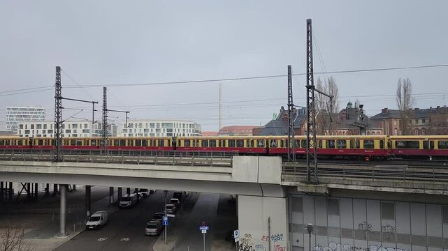 Two red and yellow commuter trains moves towards each other on a railway bridge in the city center (187)