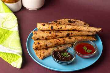 Healthy Indian Mooli or Radish paratha or stuffed flatbread with coriander and green chilli chutney on wooden background