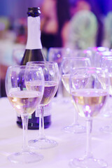 Glasses of wine and a bottle of champagne on the table with a white tablecloth.