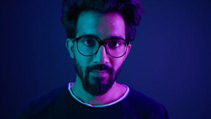 Close up portrait Arabian Indian man guy male programmer coder put on glasses 3d dimension focus gesture insight good eye sight vision focused view eyesight computer work in violet neon background